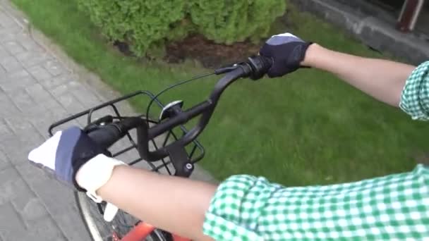 POV fiets rijden. Woonwerkverkeer op de fiets. Eerste persoon zicht op fietser. Ruiters overhandigen op fietsstuur. Een gezonde levensstijl. Handen van een jong meisje op de fiets. Handen van de vrouw pendelen op de fiets — Stockvideo