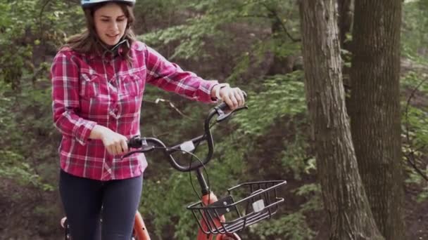 一个年轻女子把自行车推到户外的画像。清洁、可持续的城市交通。美丽的女性微笑着推着自行车和篮子。一次减少一个周期的碳排放 — 图库视频影像