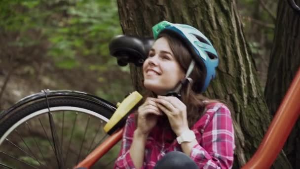 Велосипедный шлем. Женщина надевает велосипедный шлем на улице во время езды на велосипеде. Девушка надела велосипедный шлем на улице во время езды на велосипеде. Безопасная поездка на велосипеде. Защита головы. Безопасность на дороге — стоковое видео