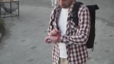 Modern binanın yakınlarında katlanmış elektrikli scooterla yürüyen bir adam. Ekolojik teknolojik yaşam tarzı. E-Hareket kabiliyeti. Elektrikli Scooter 'ı taşıyan kişi katlanmış pozisyonda. Çevre taşımacılığı