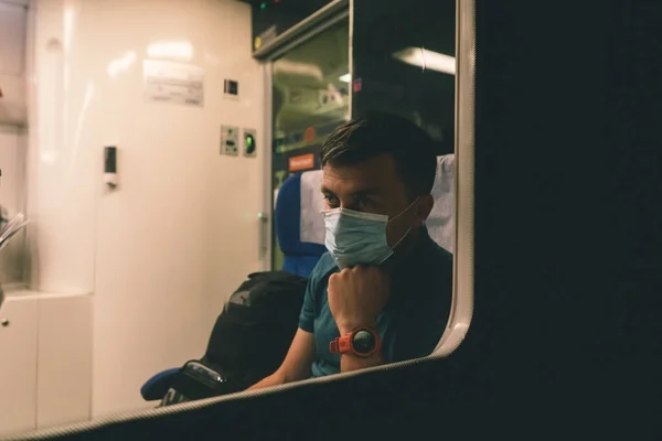 Sad man wears protective mask in train to protect the respiratory system from coronavirus infection, covid-19. Preventive measure. New normal. Travel safely on railway public transport.
