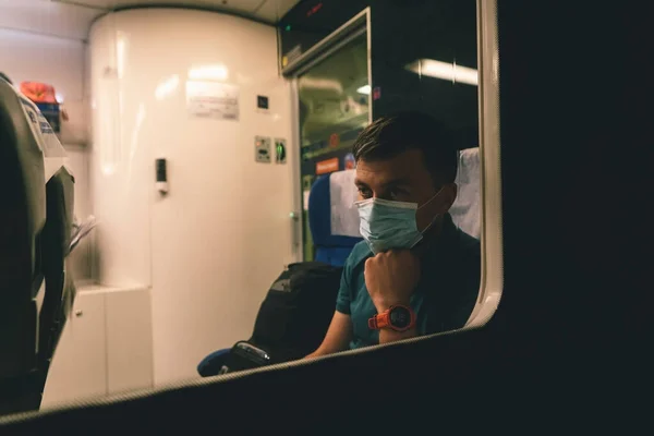 Sad man wears protective mask in train to protect the respiratory system from coronavirus infection, covid-19. Preventive measure. New normal. Travel safely on railway public transport.