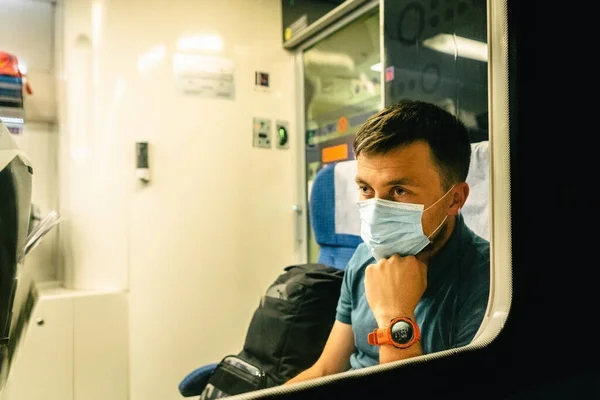 Sad man wears protective mask in train to protect the respiratory system from coronavirus infection, covid-19. Preventive measure. New normal. Travel safely on railway public transport.