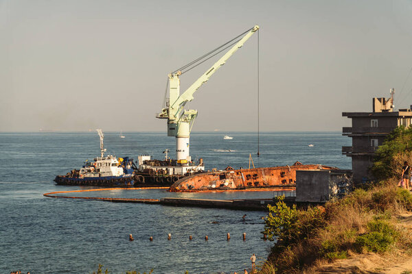 Спасатель потерпел крушение нефтяного танкера Delfi в Одессе, Украина 26 августа 2020 года, недалеко от побережья Черного моря. Морской кран разбивает Дельфи в море. Старый ржавый корабль сел на мель, буксир вытащил корабль после аварии..