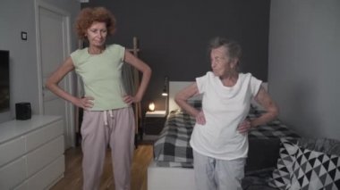 Evde kıdemli kadın ve yetişkin kız egzersizlerinin tadını çıkarıyorum. Sağlıklı yaşam tarzı kavramı. Yaşlı kadın. 90 yaşında. Hemşire rehabilitasyon için egzersiz yapıyor. Bakımevinde sağlıklı bir vücut.