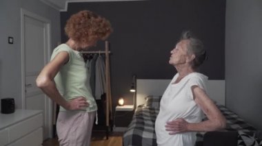 Yatak odasında kızıyla fizik tedavi gören yaşlı bir kadın. Evde, karantinada hoş vakit geçirmek. Aile spordan, sağlıklı bir yaşam tarzından hoşlanır. Evde hemşireyle son sınıf bayan antrenmanı.