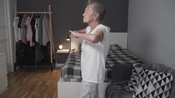 O femeie în vârstă care efectuează exerciții de antrenament pentru a reduce stresul în timpul pandemiei Covid-19, pentru a preveni coronavirusul, o femeie în vârstă sănătoasă, o fitness de sănătate superioară, rămâneți acasă. Vârsta nu este o scuză pentru a slăbi sănătatea — Videoclip de stoc