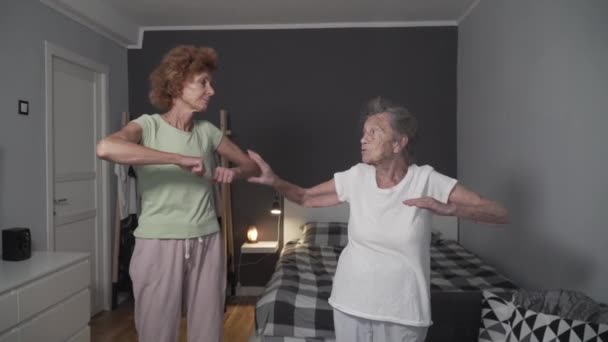 Godersi l'esercizio di donna anziana e figlia matura a casa. Un concetto di stile di vita sano. Vecchia femmina 90 anni insieme infermiera che fa esercizi per la riabilitazione, corpo sano in camera casa di cura — Video Stock