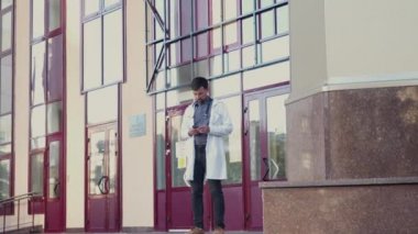 Laboratuvar önlüklü genç doktor cep telefonuyla konuşuyor, hastane merdivenlerini terk ediyor. Hastaneden cep telefonuyla çıkan bir tıp çalışanı. Tıp fakültesi öğrencisi binadan çıkarken akıllı telefon kullanıyor.