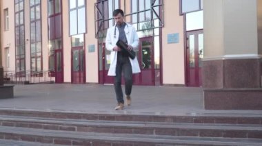 Steteskop giyen doktor dışarıda hastane girişinin yanında röntgen görüntülerini analiz ediyor. Genç sağlık uzmanı, internet radyologu COVID 19 salgını sırasında MRI-ray ciğerlerini muayene ediyor.