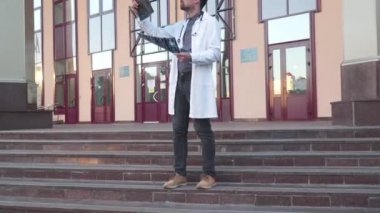 Steteskop giyen doktor dışarıda hastane girişinin yanında röntgen görüntülerini analiz ediyor. Genç sağlık uzmanı, internet radyologu COVID 19 salgını sırasında MRI-ray ciğerlerini muayene ediyor.