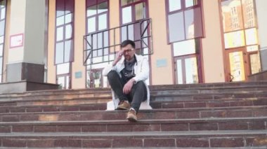 Stresli doktor. Erkek doktor gözlerini dinlendirmek ve işten uzaklaşmak için gözlüklerini çıkarıyor. Yetişkin doktor uzun saatler çalışıyor. Hayat kurtarmak zor iş. Laboratuvar önlüklü doktor gözlerini ovuyor.