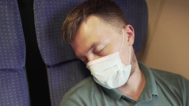 Kaukasische männliche Zugpassagiere, die während der Coronavirus-Pandemie und Epidemie müde am Fenster schliefen. Der Reisende trägt eine Schutzmaske gegen Covid-19-Infektion — Stockvideo