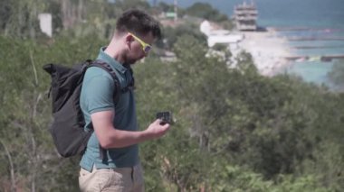 Adam, deniz kenarındaki bir dağda gün boyu yürüyüş yaparken GPS cihazıyla akıllı telefon kullanıyor. Erkek yürüyüşçü, sahil yolundaki telefondaki harita uygulamasında doğru rotayı kontrol eder