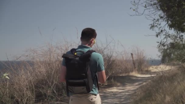 Man checking his cell phone during hiking trip. Young male using his mobile phone gps while out hiking along the path along the sea on a hill. Traveler view route on navigator in smart phone app map — Stock Video