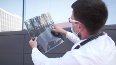 Erkek doktor, hastanın göğüs röntgenini tomografi filmiyle inceliyor. COVID-19 'da vücut röntgeni testi, Coronavirus virüsü salgını için MRI taraması. Tema akciğer radyografisi
