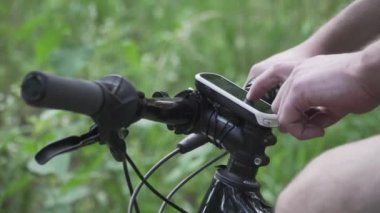 Dağ bisikletindeki GPS cihazı. GPS bilgisayarı devrede. Planlama rotası. Bisiklet dümencisiyle. Spor bisikletli araçlar. Bisiklet yolculuğu. Adam uygulama ekran haritasına dokunup ormanı kapatıyor. İzleyici etkinliği bisikleti