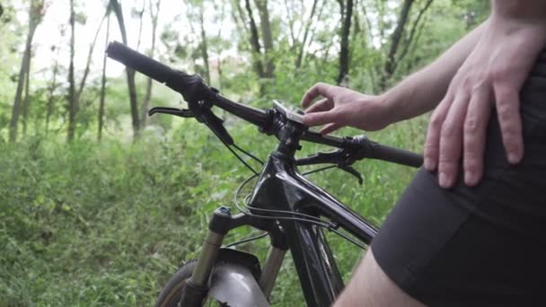 Detailní záběr cyklistických rukou používat gadget pro navigaci GPS, budování a po plánované tréninkové trase. Man touch tlačítka zařízení sledování aktivity, nahrávání stopy a navigace na řídítka kola — Stock video