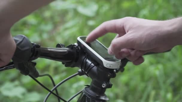 GPS пристрій на гірському велосипеді. Велосипедний GPS комп'ютер. Маршрут планування. Використання велосипедного навігатора. Гаджети на спортивному циклі. Велосипедна подорож. Хлопець торкається карти екрану програми крупним планом в лісі. Велосипед активності трекера — стокове відео