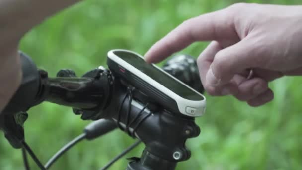 El primer plano de las manos del ciclista utiliza gadget para la navegación GPS, la construcción y el seguimiento de la ruta de entrenamiento planificada. Hombre botones táctiles dispositivo de seguimiento de la actividad, la grabación de la pista y la navegación en el manillar de la bicicleta — Vídeo de stock