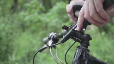 Dağ bisikletindeki GPS cihazı. GPS bilgisayarı devrede. Planlama rotası. Bisiklet dümencisiyle. Spor bisikletli araçlar. Bisiklet yolculuğu. Adam uygulama ekran haritasına dokunup ormanı kapatıyor. İzleyici etkinliği bisikleti