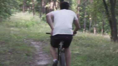 Beyaz adamın ormanda bisiklet eğitimi alırken midesi ağrır. Parkta erkek bisikletçi ishali. Sporcu, bisikleti gevşeten ağaçların arkasında eğlenecek bir yer arıyor. Acı verici bir hastalık, kendini kötü hissediyor.