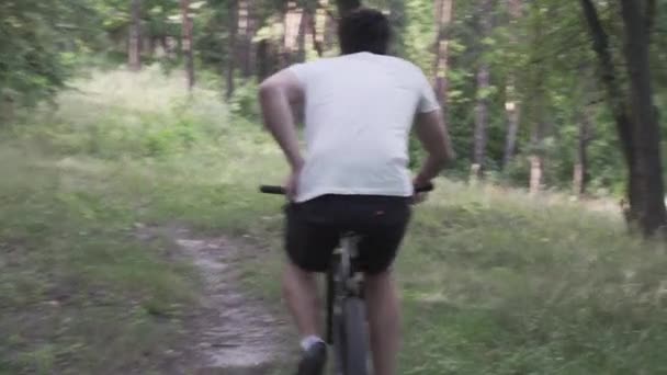 Caucasian man have stomach pain while cycling training in forest. Male cyclist diarrhea in park. Athlete looking for place to defify behind tree slacking off bike. Painful disease feeling unwell — Stock Video