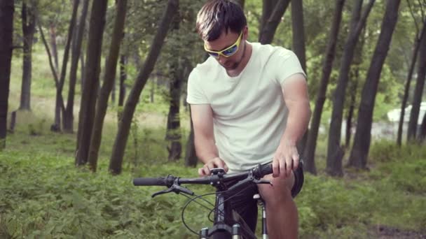 Ciclista masculino caucásico utiliza navegador GPS bicicleta para registrar la pista y seguir la ruta en el bosque. Ordenador de bicicletas con mapas fuera de línea para el turismo y los viajes en bicicleta de montaña. Gadgets en el ciclo deportivo — Vídeo de stock