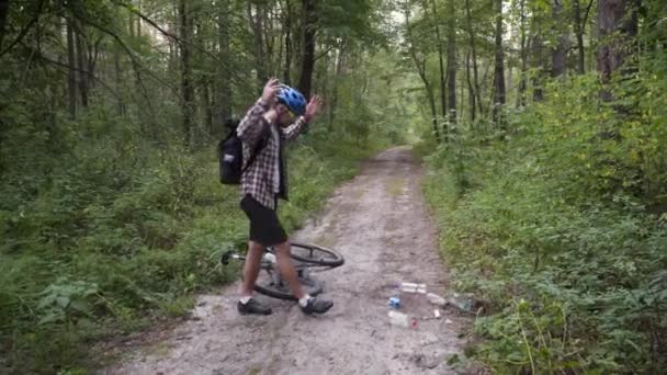 Ormanda bisiklete binip çöp toplayan bir adam. Çevreyi korumaya yardımcı olan son moda spor programları. Kirlilik. Ekolojik bir sorun. Plastik yasaklama bilinci, ulusal temizlik günü konsepti — Stok video