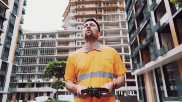 Obrero de la construcción con orejeras trabajando en la obra. Trabajador pone en los defensores de los oídos para proteger contra el sonido. Cuidar la salud, la seguridad en el trabajo. Tapones para oídos. Sonido demasiado fuerte, daño auditivo — Vídeos de Stock