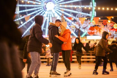 Şehir merkezinde buz pateni yapan güzel bir çift. Genç çift halka açık bir buz pateni pistinde paten kayıyor. Temalı buz pateni pisti ve sevgi dolu bir çift. İnanılmaz bir kış tatili. Sevgililer Günü.