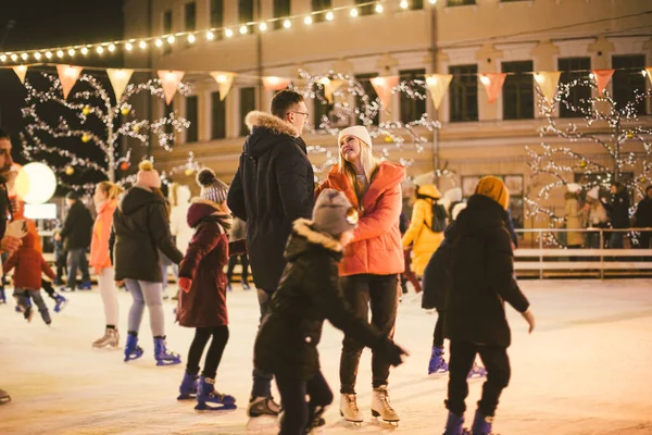 Beautiful couple have fun in ice arena. active date ice skating on ice arena in evening city square in winter Christmas Eve. St. Valentine\'s Day at the city ice rink. New Year\'s holidays in city Kiev.