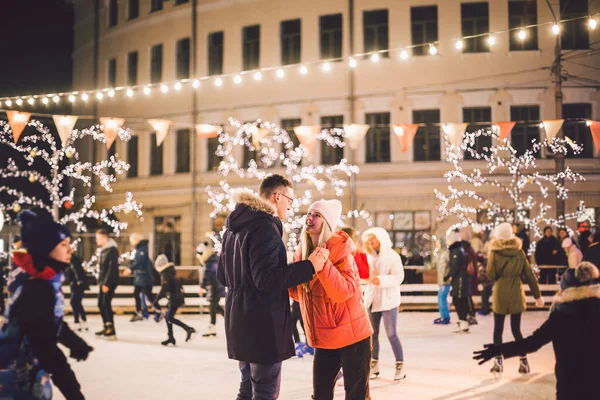 Beautiful couple have fun in ice arena. active date ice skating on ice arena in evening city square in winter Christmas Eve. St. Valentine\'s Day at the city ice rink. New Year\'s holidays in city Kiev.