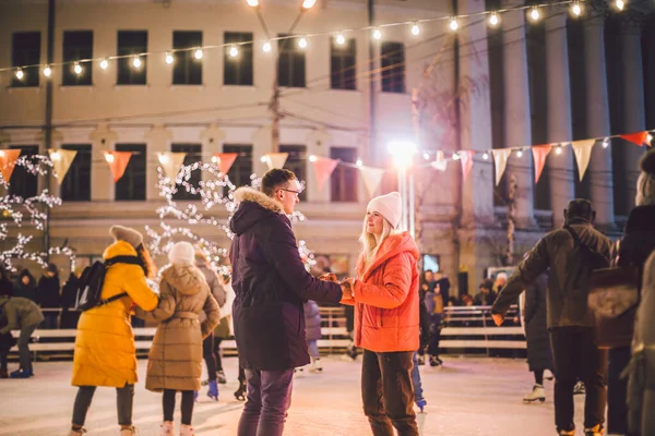 Beautiful couple have fun in ice arena. active date ice skating on ice arena in evening city square in winter Christmas Eve. St. Valentine\'s Day at the city ice rink. New Year\'s holidays in city Kiev.