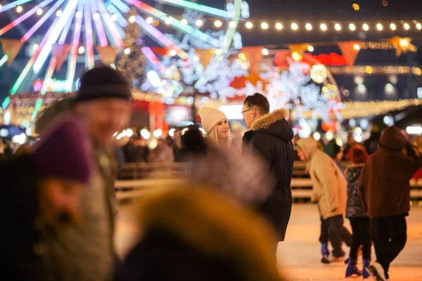 A young Caucasian couple spends the New Year and Christmas holidays in an active and sporty manner on the city ice arena on the square in the city. Romantic evening on valentine\'s day at the rink.