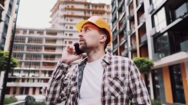 Mühendis telefonda konuşuyor. İnşaat alanında telefonu kullanan bir mimar. Foreman 'ın telefon kontrol işlemleri. İnşaat sektöründe inşaat işçisi iletişimi. Profesyonel telefon binası