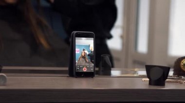 Akıllı telefon için sosyal ağ teması ve amatör video. Özçekim kamerasındaki akıllı telefon kaydı videosu yakın plan, kuaförden canlı yayın. Saç kurutma makinesi ve fırça kullanarak uzun saç kurutma makinesi.