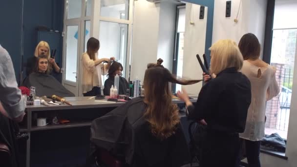 Schoonheid, kapsel concept, gelukkige jonge vrouw en kapper met strijkijzer maken kapsel in de kapsalon. Vrouw met haar gestileerde kapper. Verzacht Hair Curling. Stylist Gereedschap voor modellering gebruiken — Stockvideo