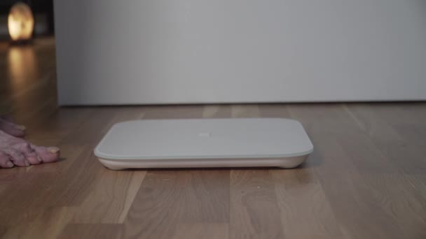 Close-up of leg of an old elderly woman getting on the electronic floor scale. A senior female with sore crooked toes and scary nails is weighed on a home scale in the living room. Healthy retirement — Stock Video