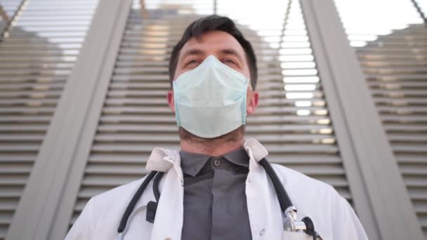 Stanco triste medico uomo caucasico togliersi la maschera medica, a riposo mentre appoggiato sulla parete. Riposo medico maschile dopo un duro lavoro. Ha perso la vita durante il Covid 19. Giornata difficile medico deluso. Faccia ravvicinata — Video Stock