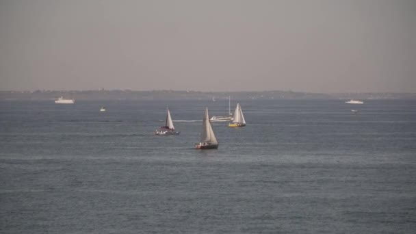 Flere seilskip seiler parallelt i Svartehavbukta mot et bakteppe av en kystby omgitt av andre skip. Temaet for sjøtransport og feriereiser til sjøs om sommeren. – stockvideo
