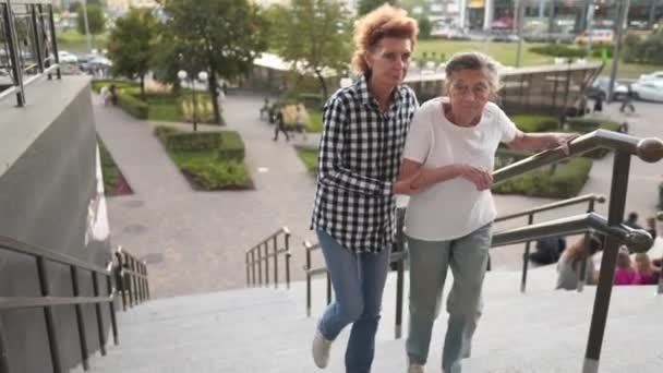 Fornire aiuto e sostegno agli anziani. Nonna, paziente. Donna che aiuta la nonna a salire le scale. Donna anziana con badante a casa. Infermiera che assiste il supporto, aiutando la donna anziana ad andare sulle scale — Video Stock