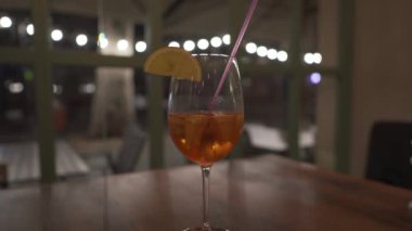 Limonlu ve şeffaf bardakta alkollü şarap kokteyli bir restoran masasının arka planında, gece şehrinde. Kulüp hayatı ve bar içkileri teması.