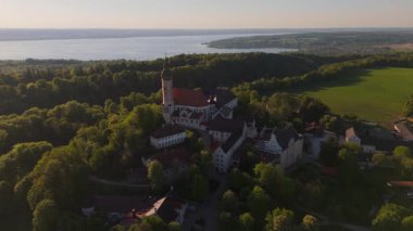 Kloster Andechs 'in ve Ammersee Gölü, Bavyera, Almanya' daki Holy Mountain 'daki kutsal kilisenin insansız hava aracı videosu. Manastır, doğa ve Münih yakınlarındaki kırsal manzaranın günbatımı manzarası