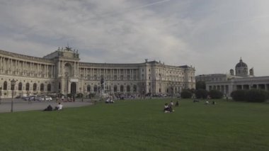 20 Ağustos 2024 Viyana, Avusturya. Hofburg Sarayı. Turistler, görkemli, tarihi binaların önündeki yeşil çimlerde dinleniyorlar. Yaz manzarası. Büyük mimari ve ünlü tarihi eser.