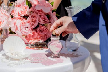 Gelin ve damat kristal vazoya renkli kumlar döküyor. Sembolik deniz dekoru merasimi sırasında okyanusun önündeki kumlu kumsalda evlilik birleşme töreni sırasında kapatılıyor. 
