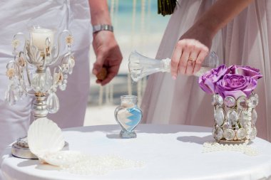 Gelin ve damat kristal vazoya renkli kumlar döküyor. Sembolik deniz dekoru merasimi sırasında okyanusun önündeki kumlu kumsalda evlilik birleşme töreni sırasında kapatılıyor. 