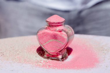 Gelin ve damat kristal vazoya renkli kumlar döküyor. Sembolik deniz dekoru merasimi sırasında okyanusun önündeki kumlu kumsalda evlilik birleşme töreni sırasında kapatılıyor. 