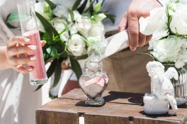 Gelin ve damat kristal vazoya renkli kumlar döküyor. Sembolik deniz dekoru merasimi sırasında okyanusun önündeki kumlu kumsalda evlilik birleşme töreni sırasında kapatılıyor. 