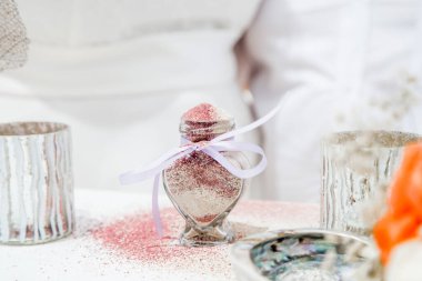 Gelin ve damat farklı renklerde kumları kristal vazonun içine döküyor. Sembolik deniz dekoru merasimi sırasında okyanusun önündeki kumlu kumsalda nikah töreninde yakın durun. 